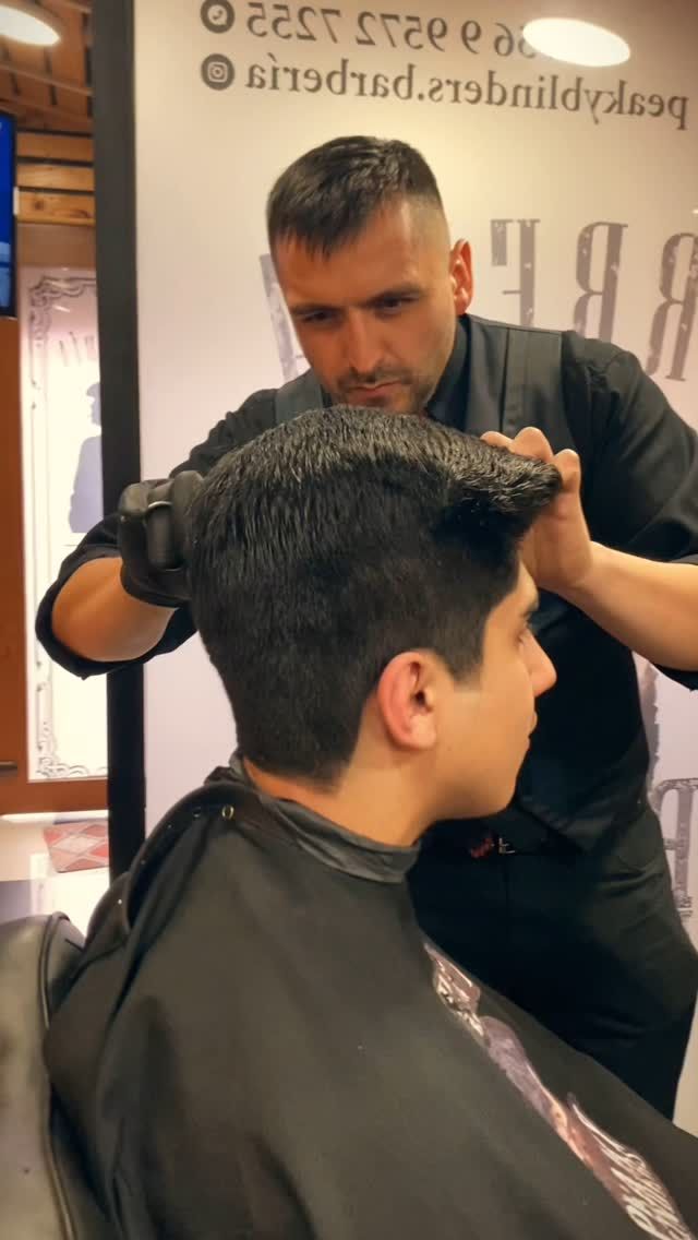 Barbero trabajando el corte de un cliente